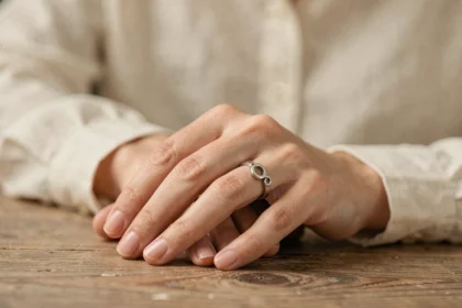 Femme portant une alliance en argent à la main droite posée sur une table en bois, symbolisant le statut matrimonial et la signification culturelle de l'alliance portée à droite